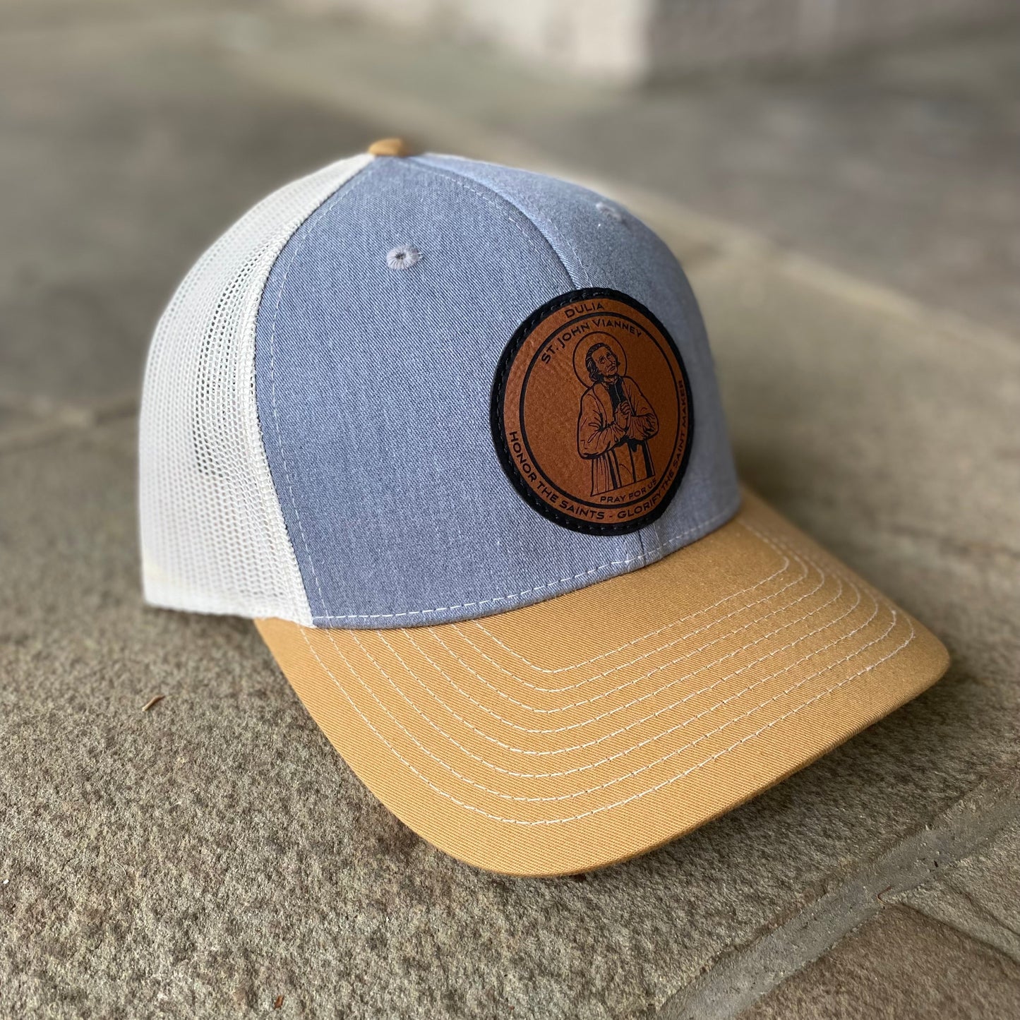 Leather patch trucker hat with St John Vianney